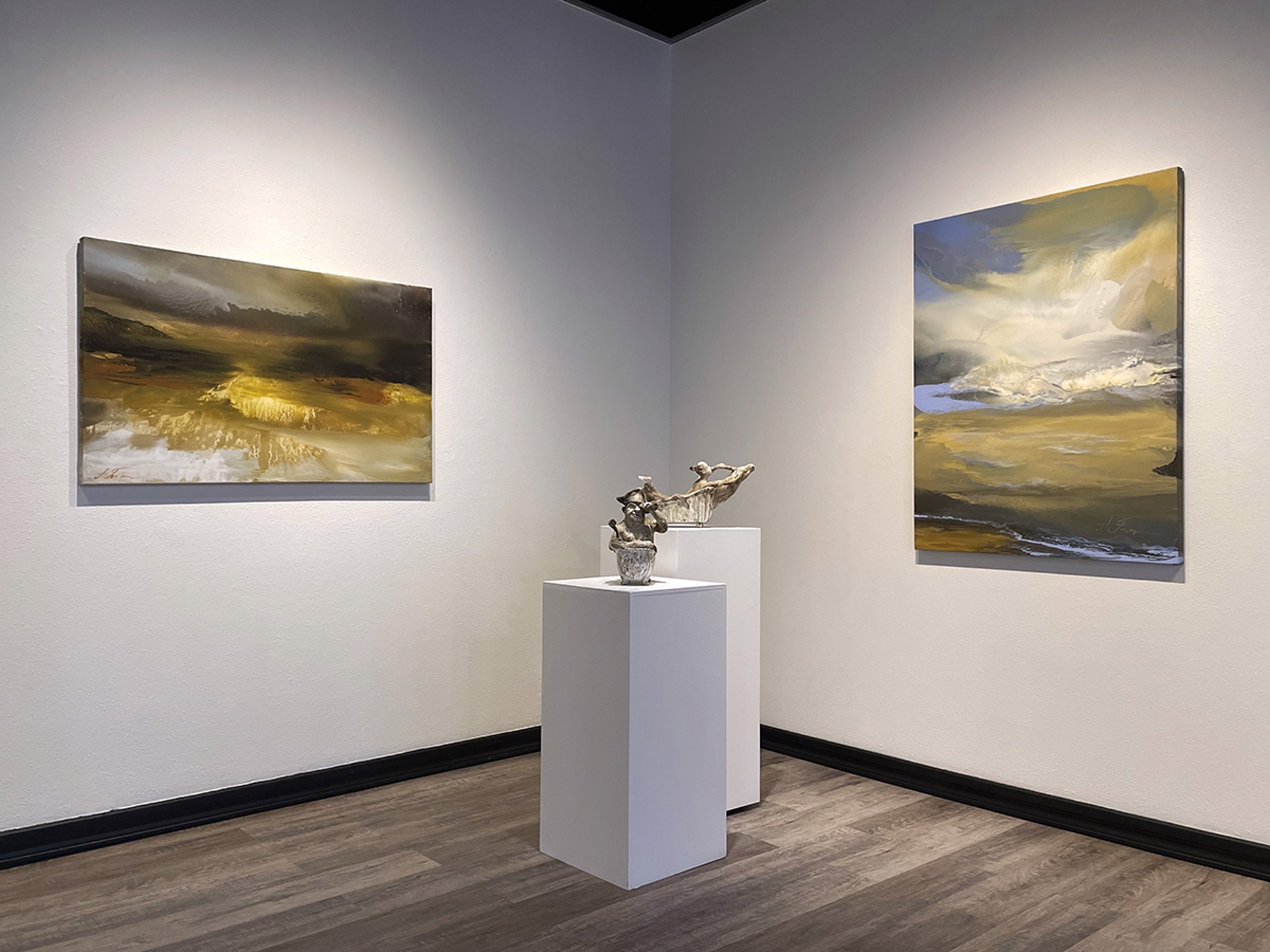 Two abstract paintings on a white wall and pedestals with small sculpture in between them.